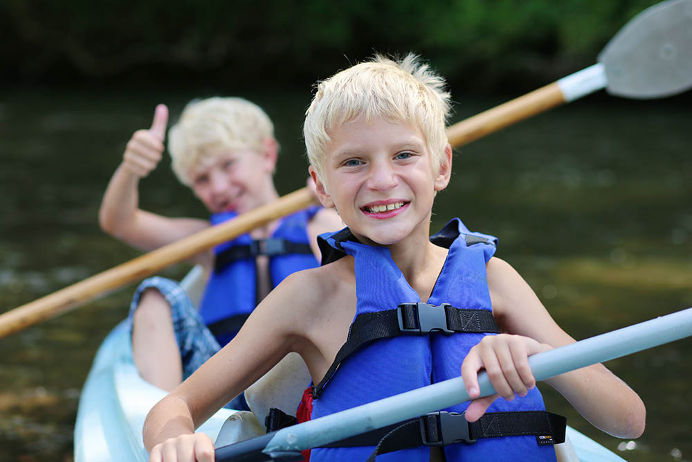 Active happy twin brothers kayaking on the river