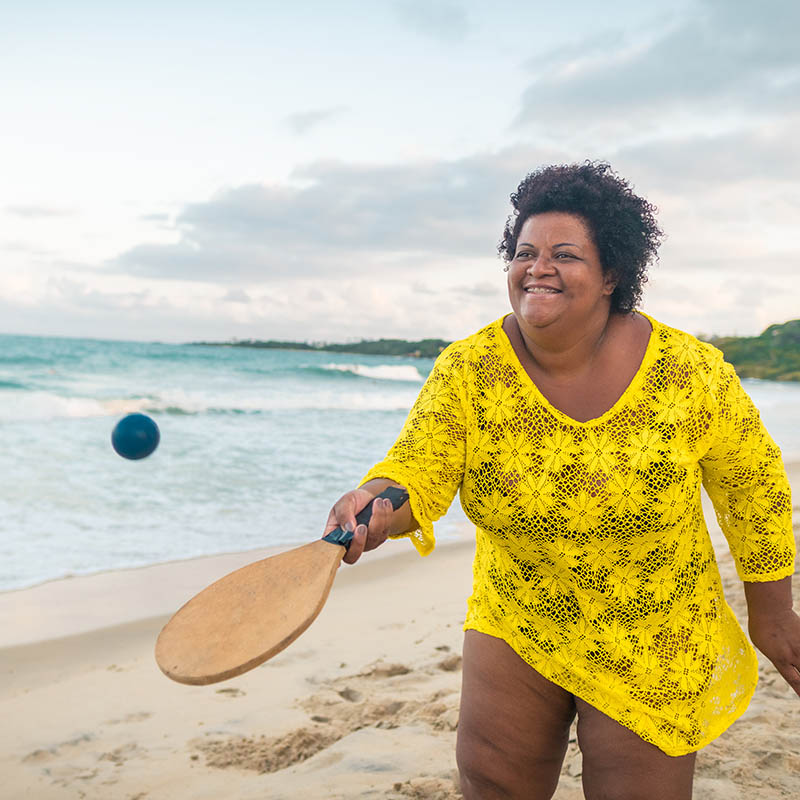 Afro woman playing beach tennis