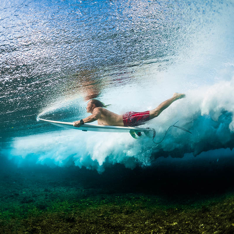 Young surfer dives under the ocean wave