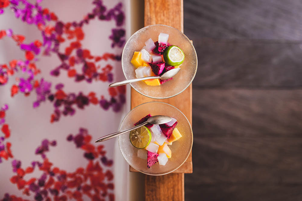 Two bowls of fruit next to a spa bath