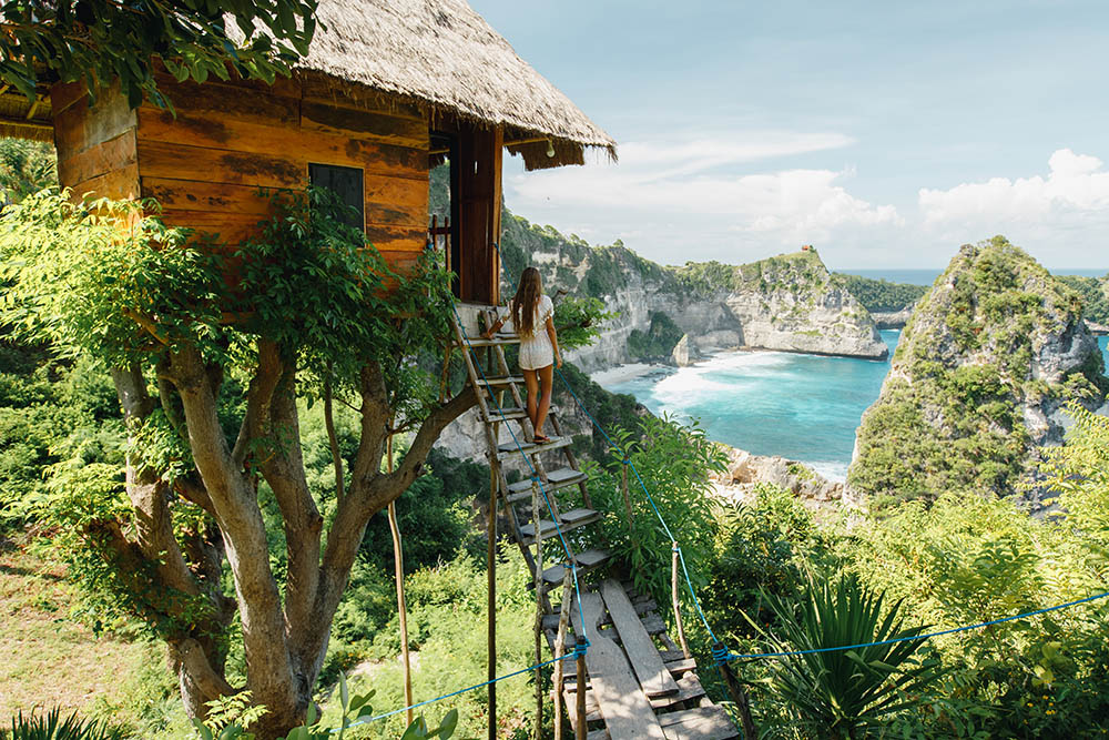 girl on steps of traditional house on tree, look at Atun beach, Nusa Penida island, Indonesia