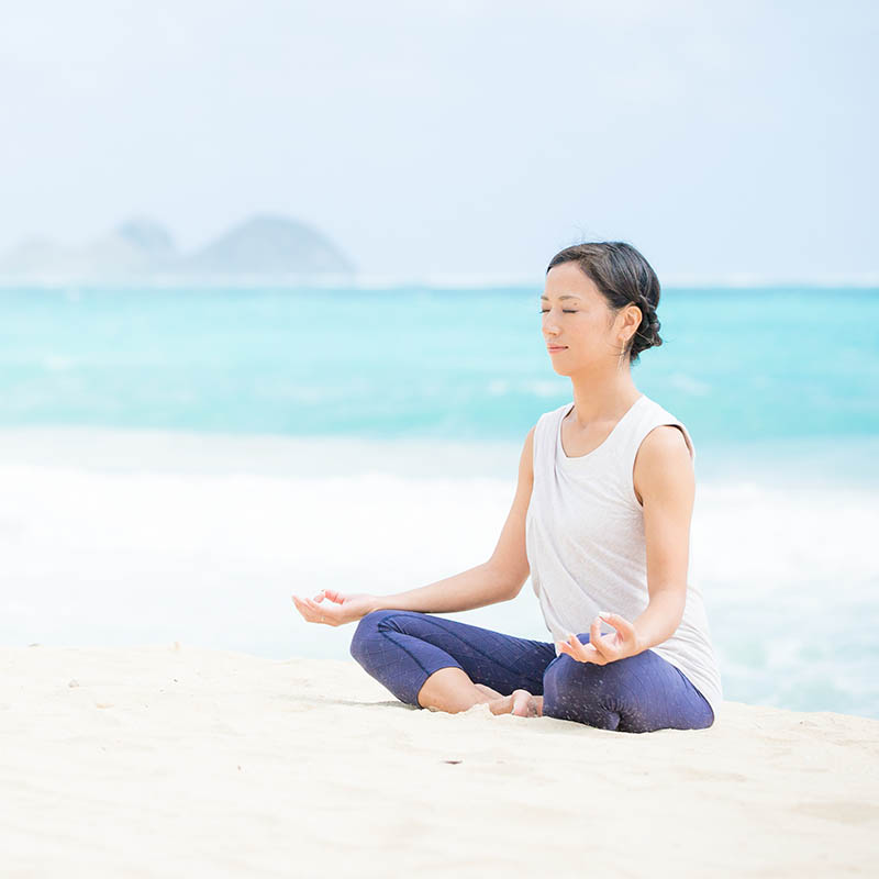 Japanese woman on a beach doing yoga