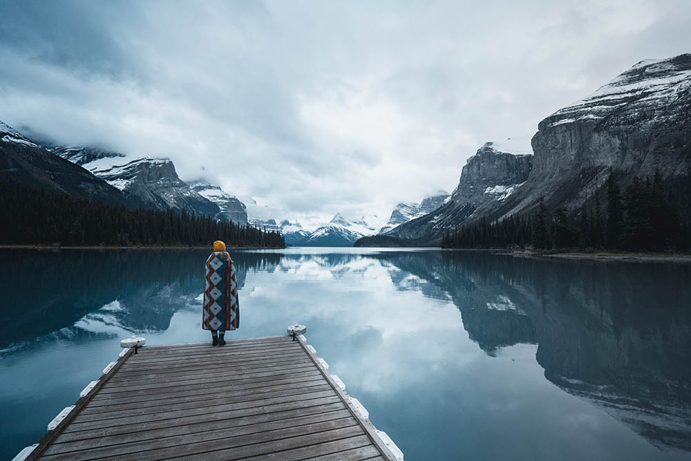 Woman in a blanket looking at a lake in Canada