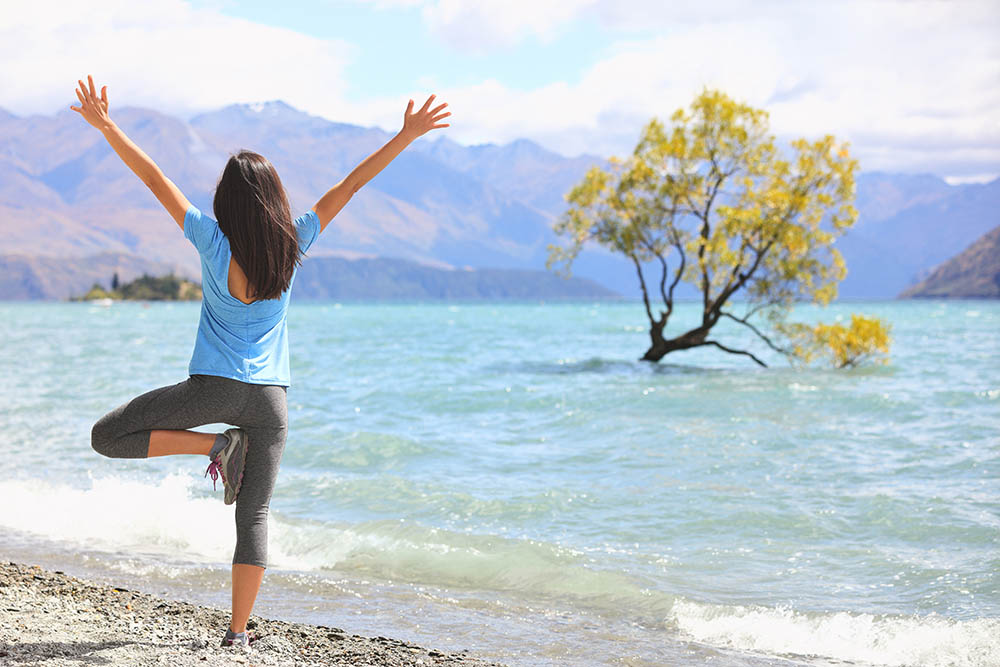 Woman doing yoga practice at Wanaka lake, New Zealand