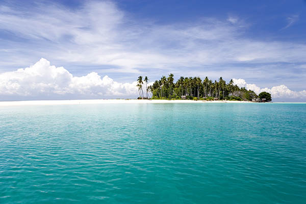 Image of a remote Malaysian tropical island with deep blue skies, crystal clear waters,  huts and coconut trees.