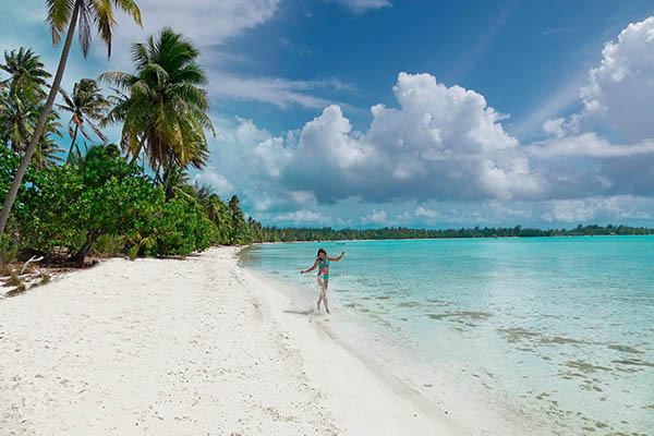 girl splashing ocean water while walking along the beach on an island in the South Pacific