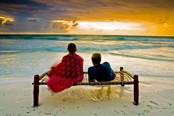 Romantic couple sitting looking at the sea on a beach in Zanzibar, Tanzania