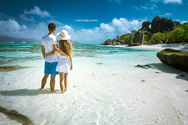 A young couple standing in shallow water on La Digue island, Seychelles