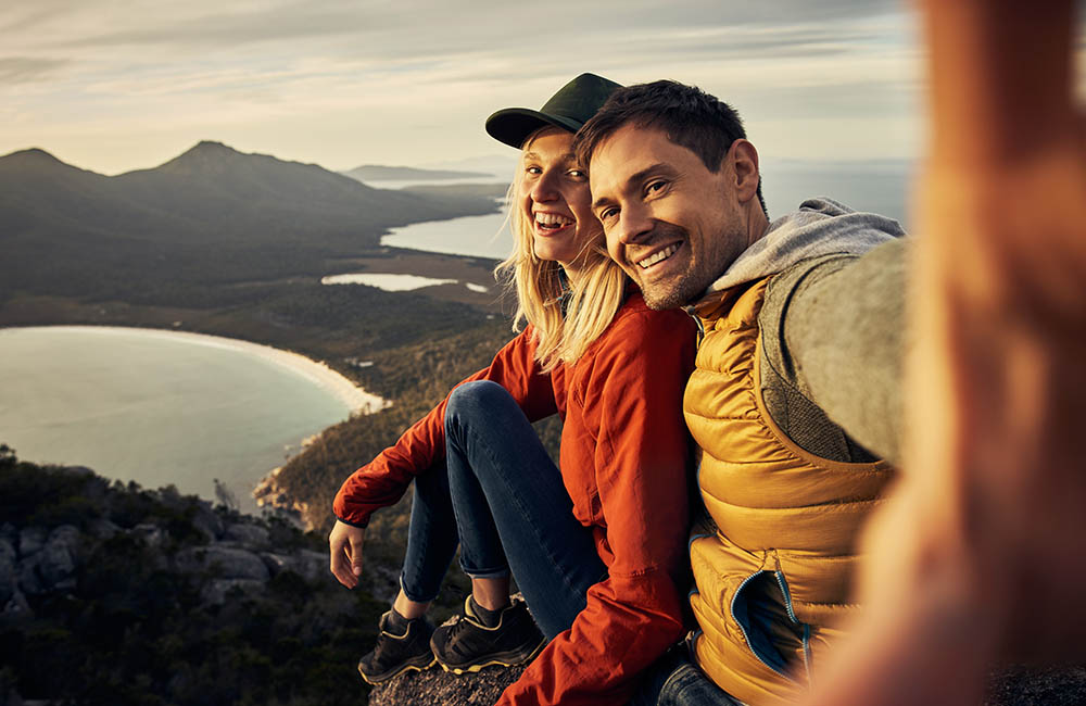 honeymoon  couple taking selfies overlooking Wineglass Bay in Tasmania