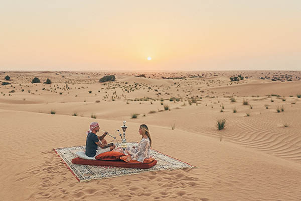 Honeymoon couple seating on a carpet in the Emirates desert