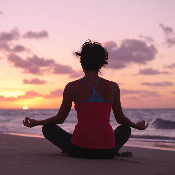 Young woman practicing yoga on a beach at sunrise