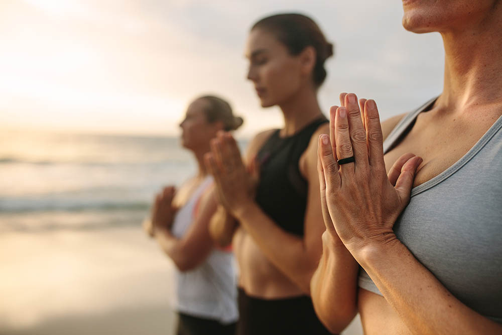 Three women meditating at the beach