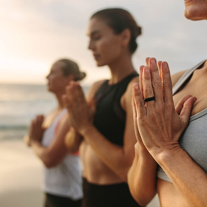 Three women meditating at the beach