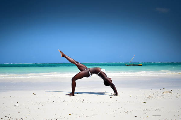 African girl doing a yoga pose on the beach in Africa