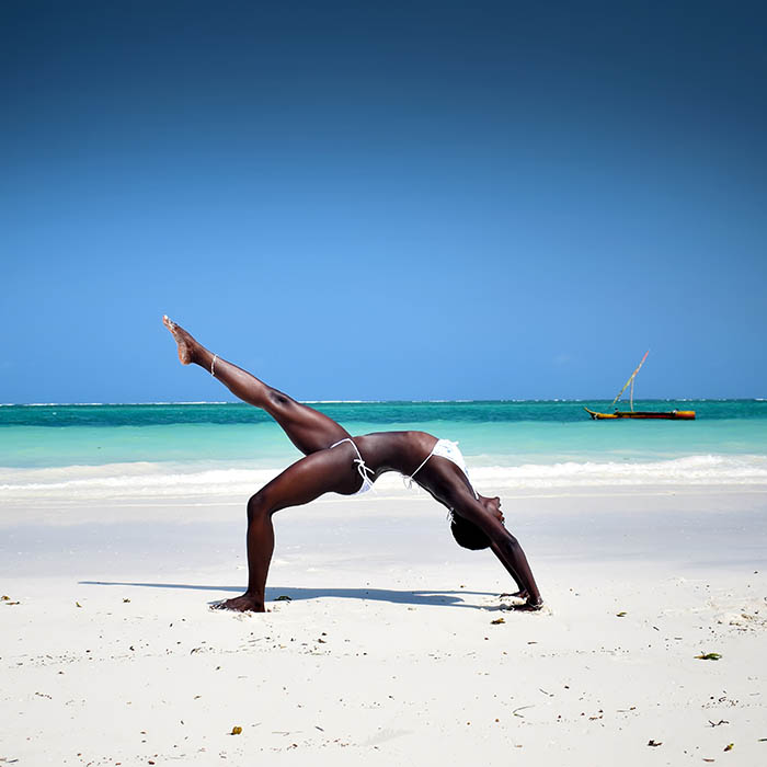 African girl doing a yoga pose on the beach