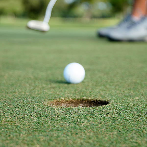 Close-up shot of someone putting a golf ball