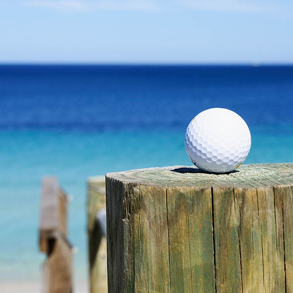 Golf ball on a wooden post by the sea