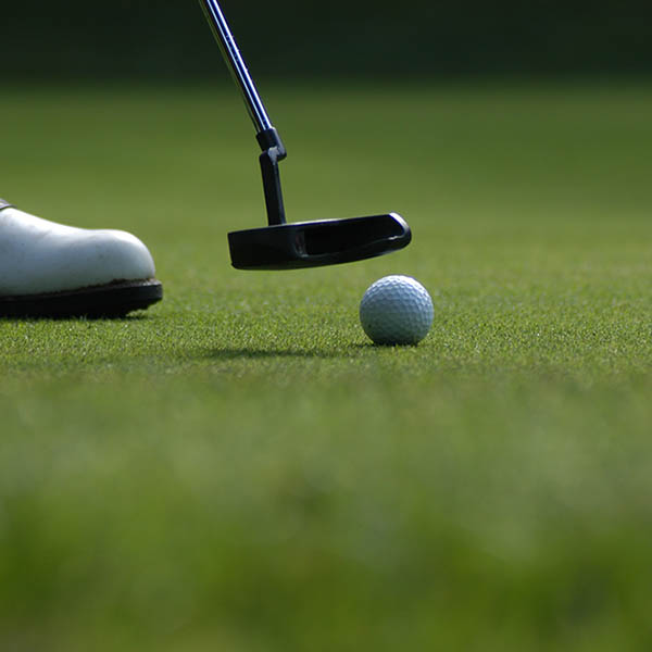 Close-up of golf club about to hit a golf ball