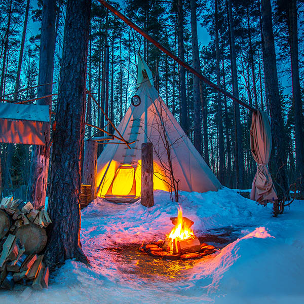 Native Canadian tipi in the forest with snow and a bonfire