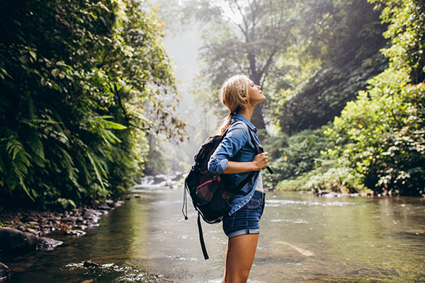 Relaxed female hiker standing in a stream