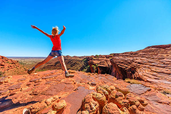 Young hiking girl jumping in Watarrka National Park. King Canyon Rim Walk at sunset. Northern Territory, Australia