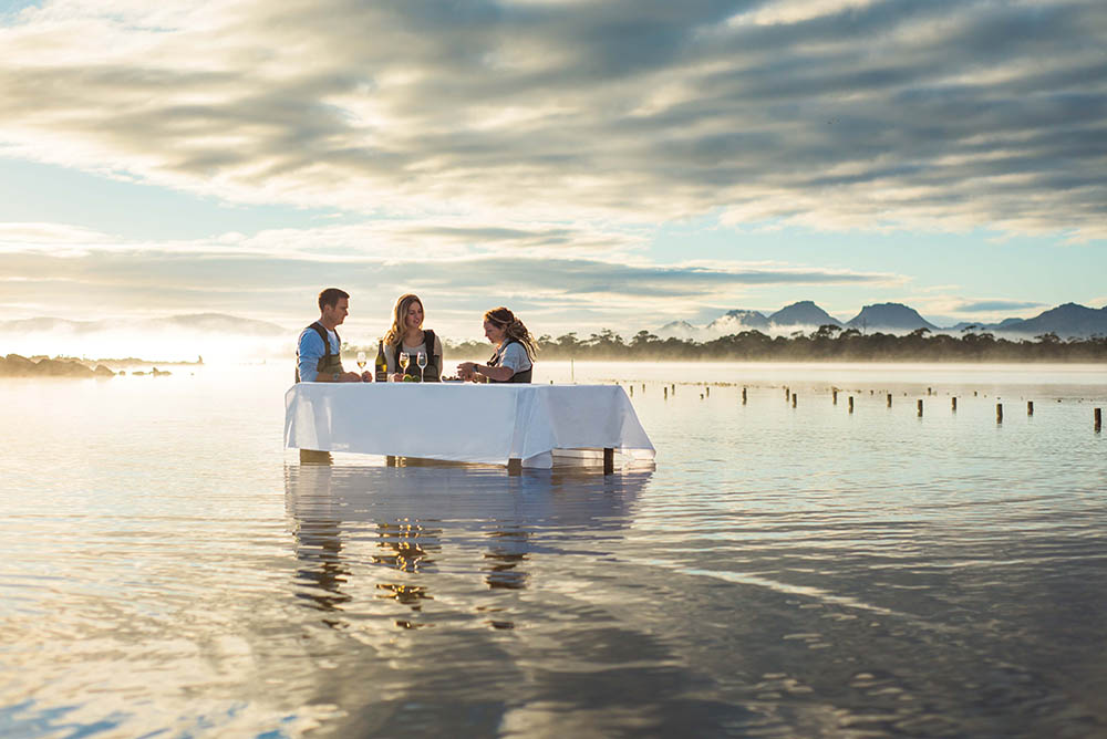 A honeymoon couple sitting at a table in the water Oyster Shucking at Saffire Freycinet, Tasmania