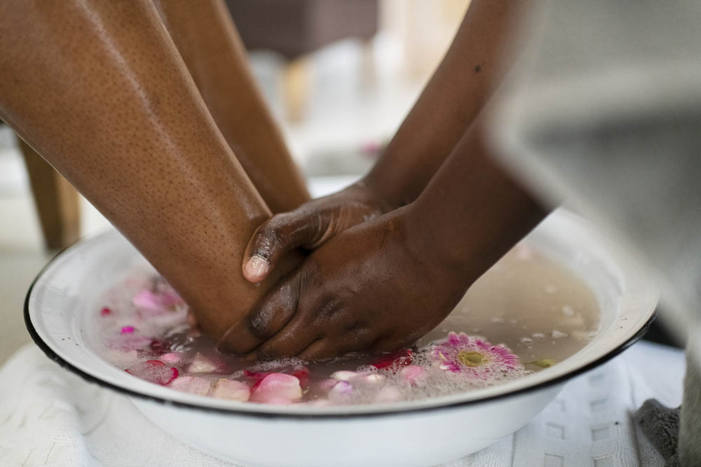 Close up woman's feet in foot bath at spa with petals