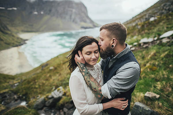 Happy wedding couple on a hill overlooking Kvalvika beach in the Lofoten Islands, Norway