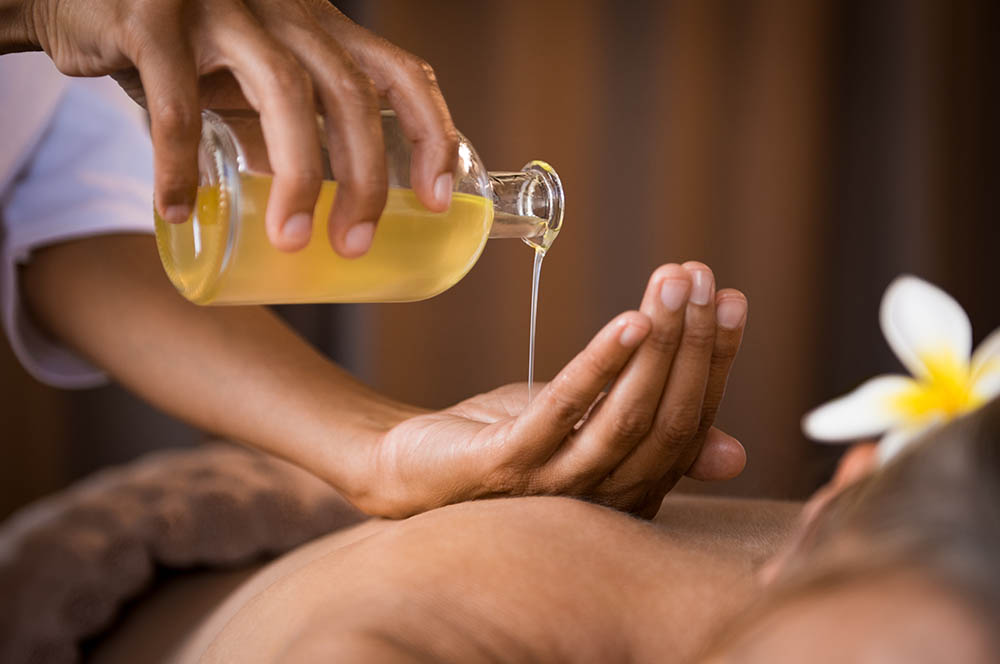 Closeup of masseur hands pouring aroma oil on a woman's back