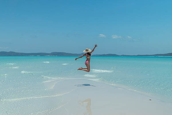 Woman jumping on Whitsundays beach, Whitsundays Islands, Australia