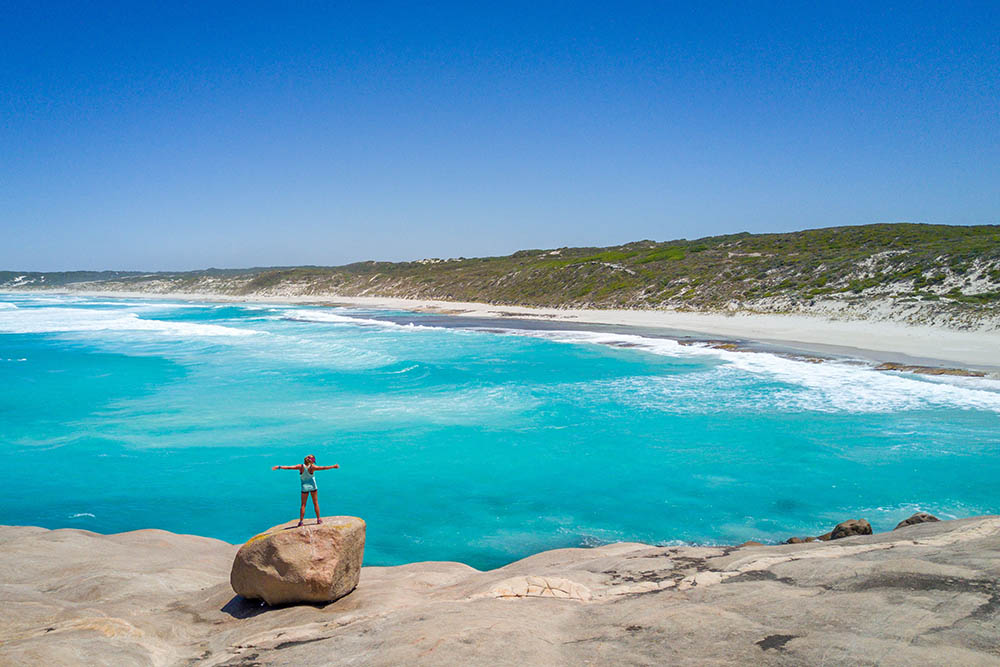 Woman standing on a rock by the sea in Esperance, Western Australia