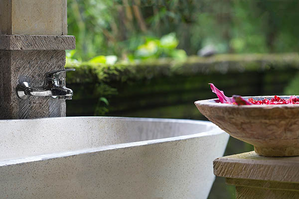 Close up of an outdoor spa bath with a bowl of pink flowers