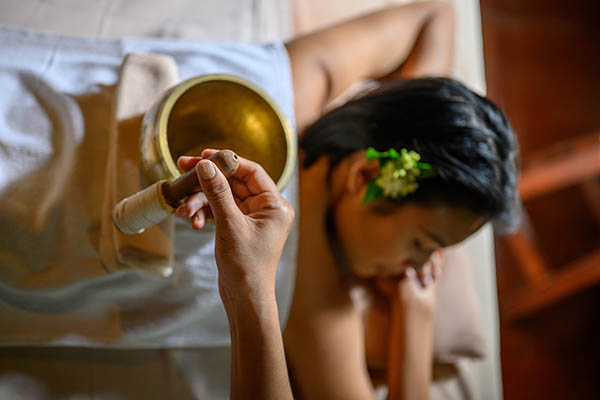 Directly above view of young asian woman relaxing with Tibetan singing bowls treatment in spa salon