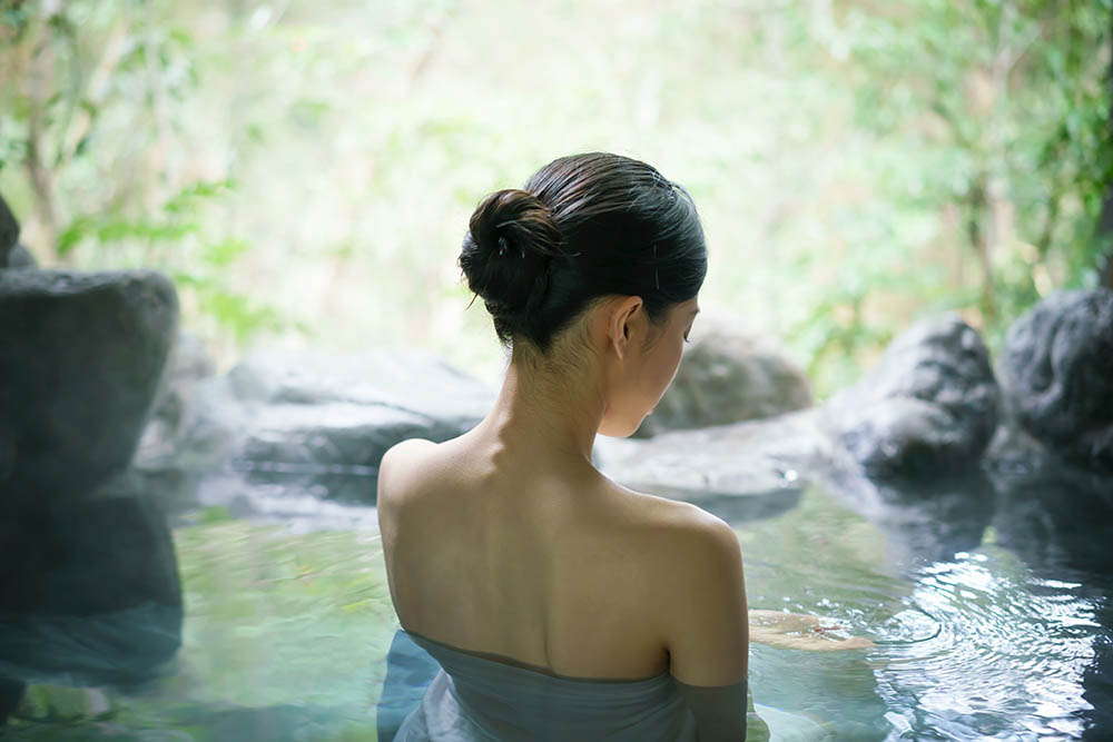 Back view of a young Japenese woman in a hot spring in Japan