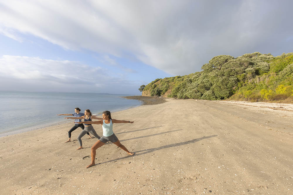 Three woman practicing yoga on Motuihe Island, Hauraki Gulf, New Zealand