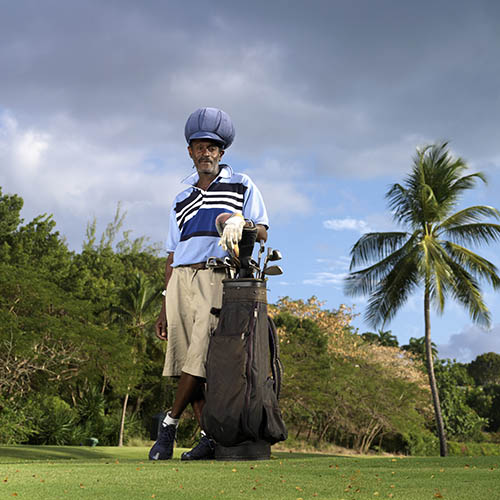 Rastafarian golfer standing next to his golf clubs on a golf course in the Caribbean