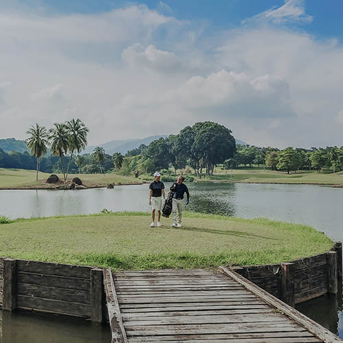 Father and son playing golf in melaka, malaysia walking toward carrying golf set