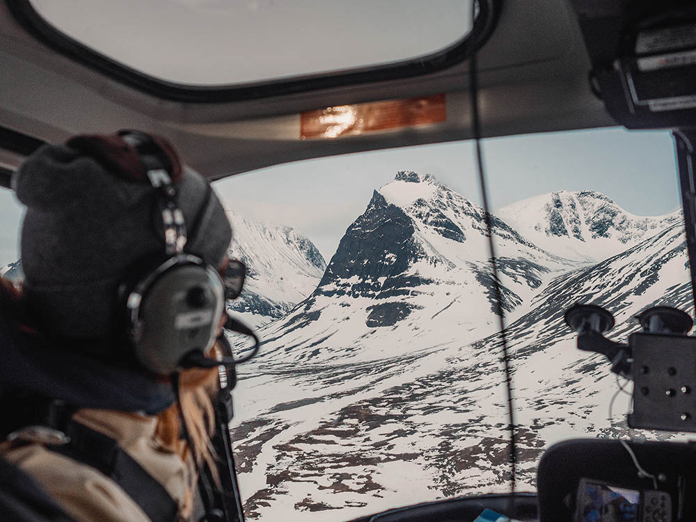 Girl looking out on a snowy crater mountain from a helicopter