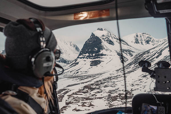 Girl looking out on a snowy crater mountain from a helicopter