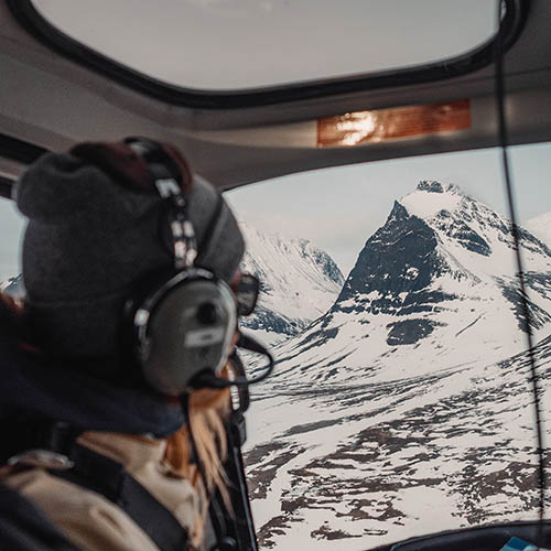 Girl looking out on a snowy crater mountain from a helicopter