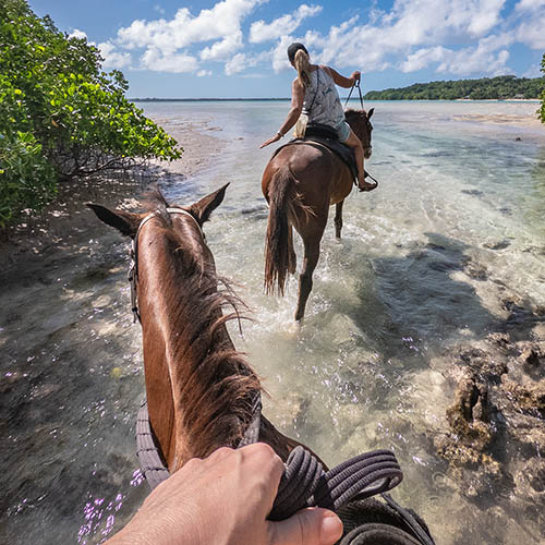 Horse riding through a lagoon on Espiritu Santo, Vanuatu