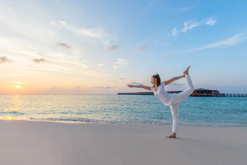 Woman practicing yoga on a beach in the Maldives