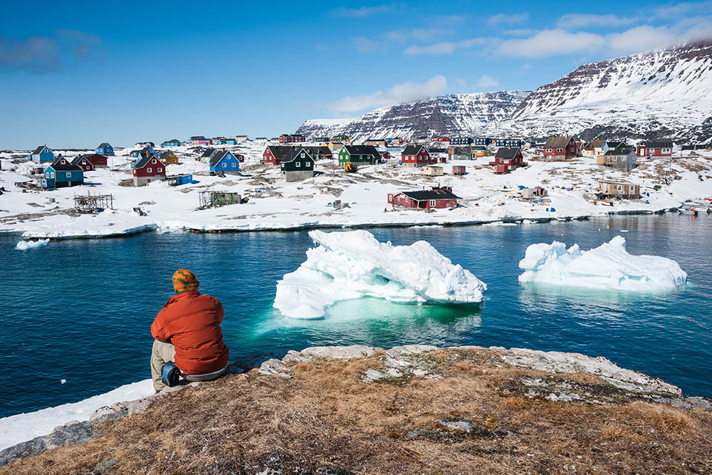 Tourist looking at views of Qeqertarsuaq, a small town in Greenland in early spring time