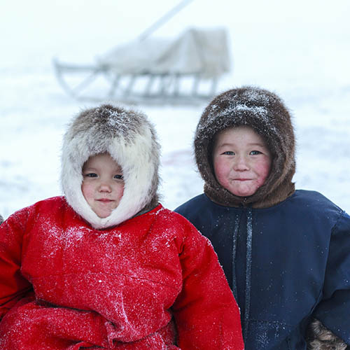 Children in national clothes in the snow with a sleigh in the background