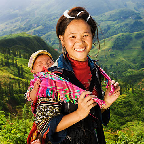 Black Hmong woman looking at the view & carrying her baby