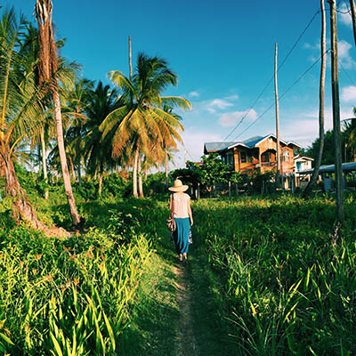 Woman walking through a field to a village in Guyana