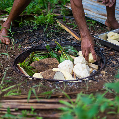 Man preparing food on an Umu underground oven in Tonga