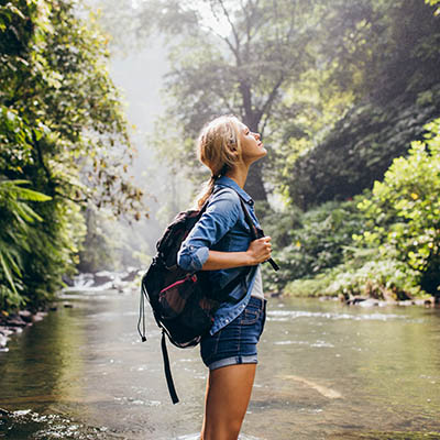 Relaxed female hiker standing by the stream