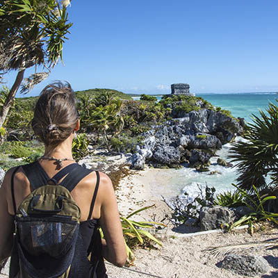 Woman taking in a view of El Castillo and the Caribbean coast. Mayan site of Tulum. Quintana Roo, Mexico.