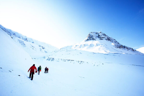 Group of people hiking across a winter landscape in Svalbard